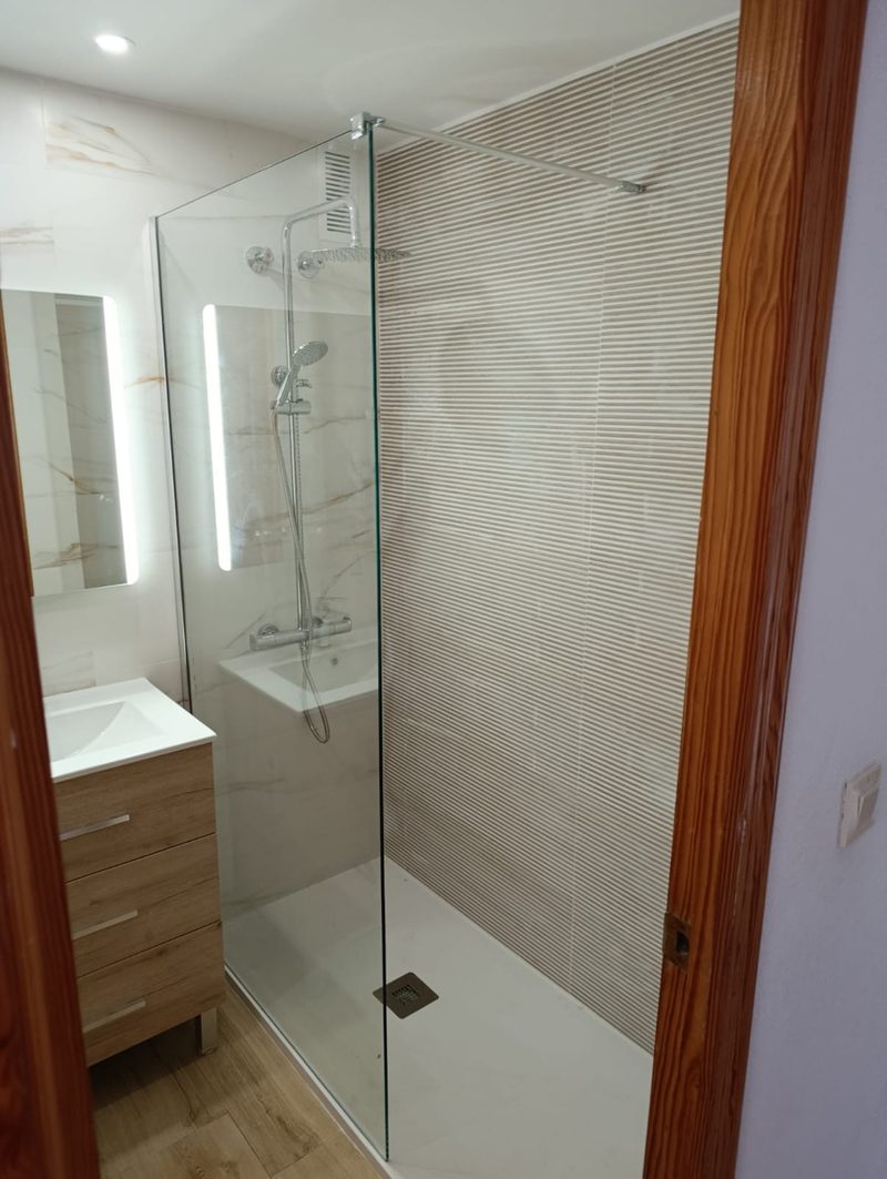 Reforma de baño en la Albufereta (Alicante): plato de ducha a ras de suelo, mampara fija de cristal y columna de ducha con rociador
